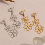 Pair of silver and gold floral earrings with pearl-like beads on a beige background