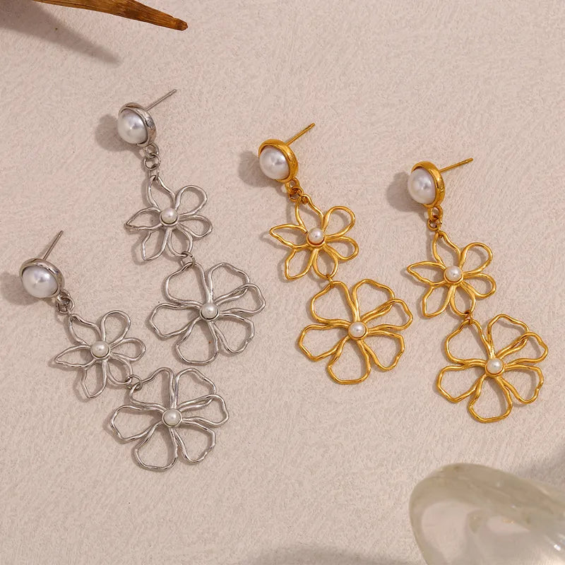 Pair of silver and gold floral earrings with pearl-like beads on a beige background