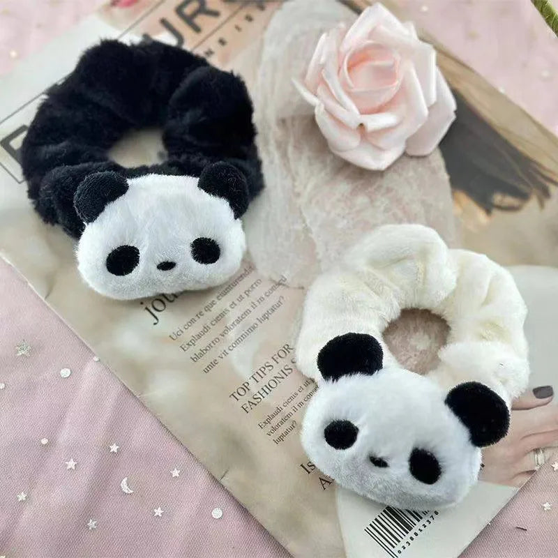 Two panda-shaped hair accessories on a surface with a pink flower and newspaper.