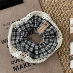 Plaid scrunchie with lace trim on a textured surface