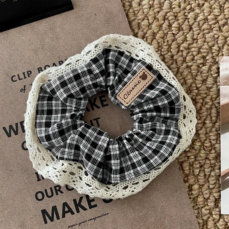 Plaid scrunchie with lace trim on a textured surface