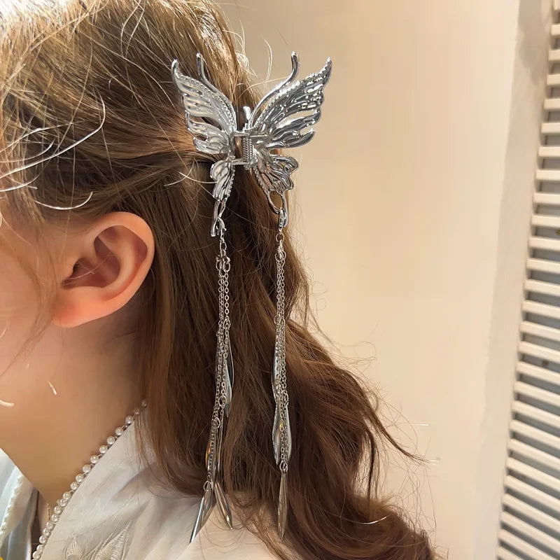 Butterfly hair accessory with chains in a person's hair against a neutral background