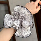 Laceroupon held by a hand against a neutral background, scrunchies worn on hand