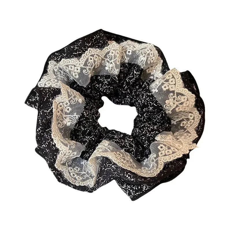 Black scrunchie with lace detailing on a white background