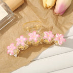 Clear hair clip with pink floral designs on a textured surface