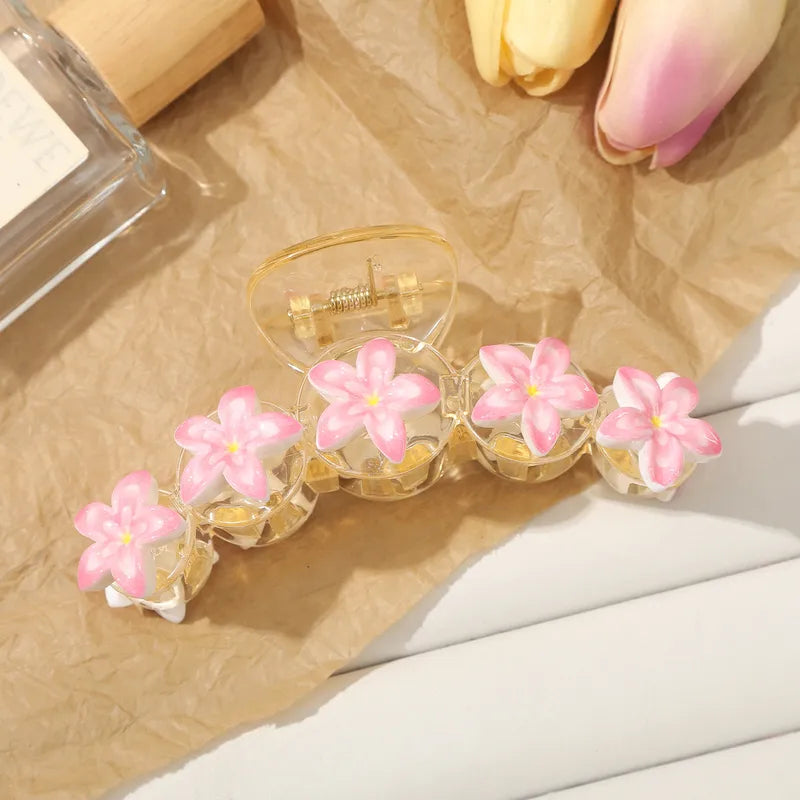 Clear hair clip with pink floral designs on a textured surface