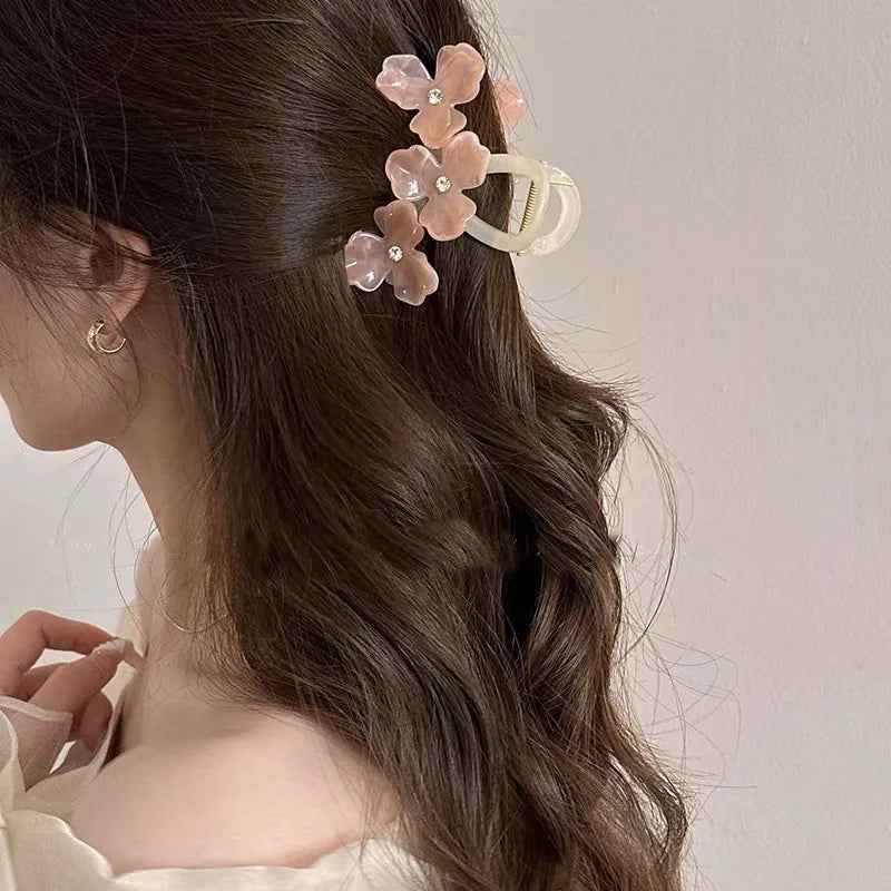 Woman with wavy hair wearing a floral hair clip against a neutral background