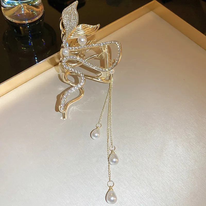 Gold leaf-shaped clip with pearl drops on a white surface