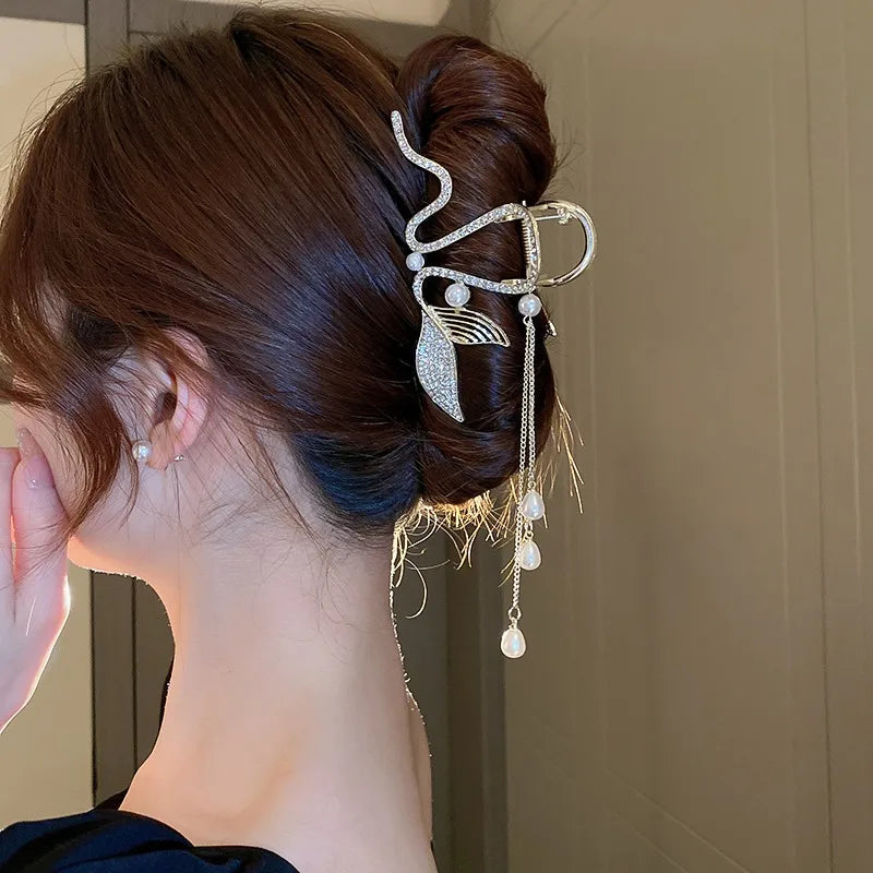 Woman with an elegant hair bun adorned with a decorative hairpin against a neutral background