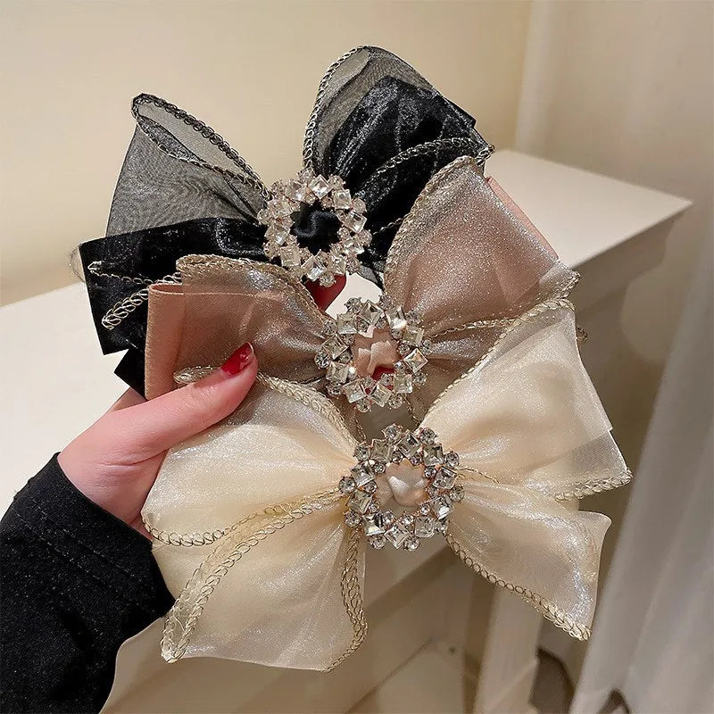 Decorative bow with crystals held by a hand against a neutral background