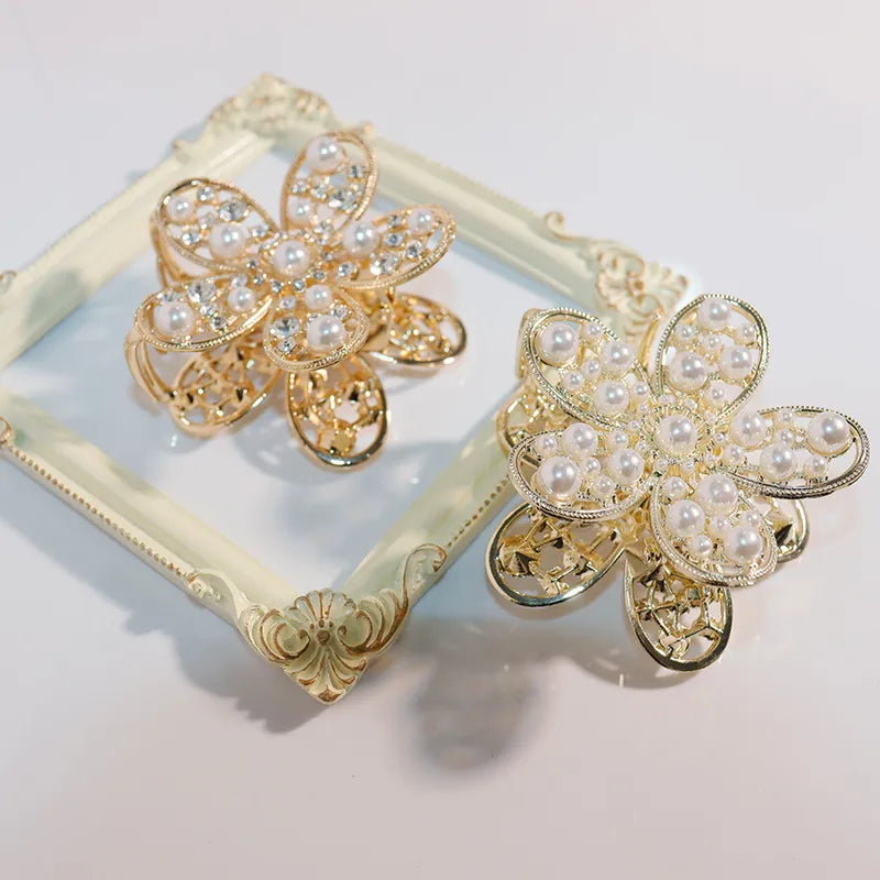 Gold and pearl flower-shaped hair clips on a decorative mirror.