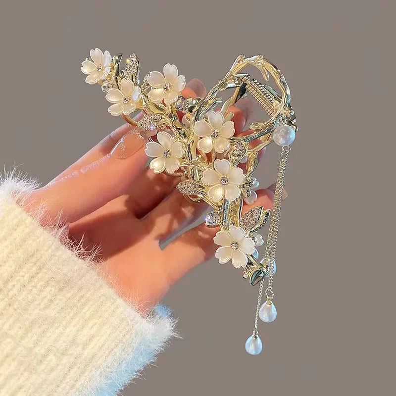 Decorative headband with floral elements held by a hand against a neutral background