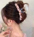Person with a hair bun adorned with pink heart-shaped hair clips against a neutral background
