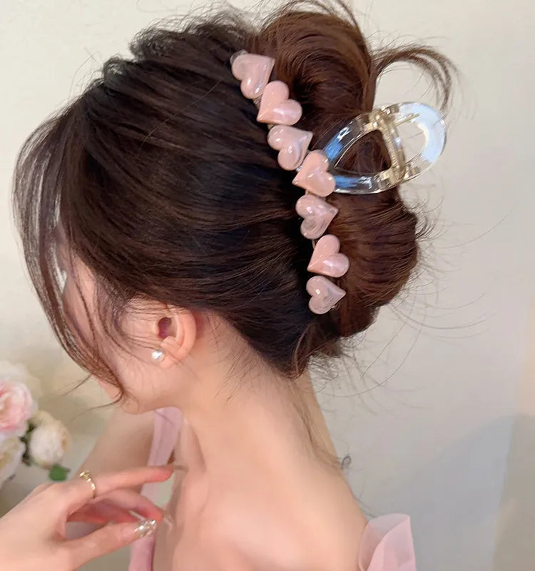 Person with a hair bun adorned with pink heart-shaped hair clips against a neutral background