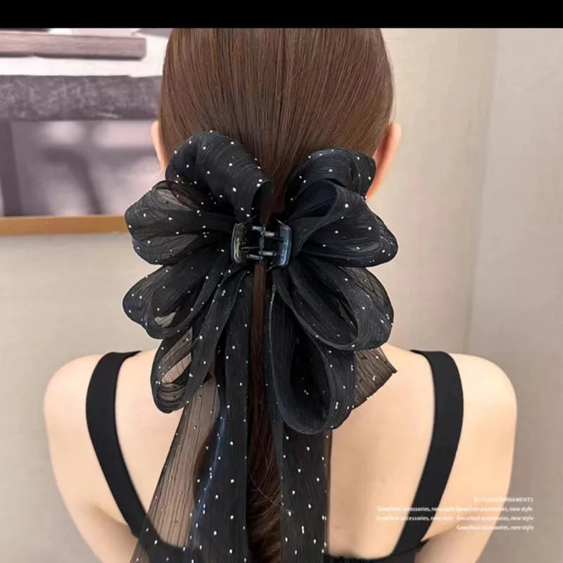 Black floral hair accessory on a person with a neutral background