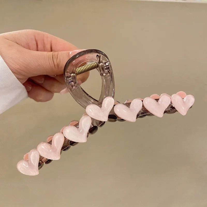 Hair clip with heart-shaped beads held by a hand against a beige background
