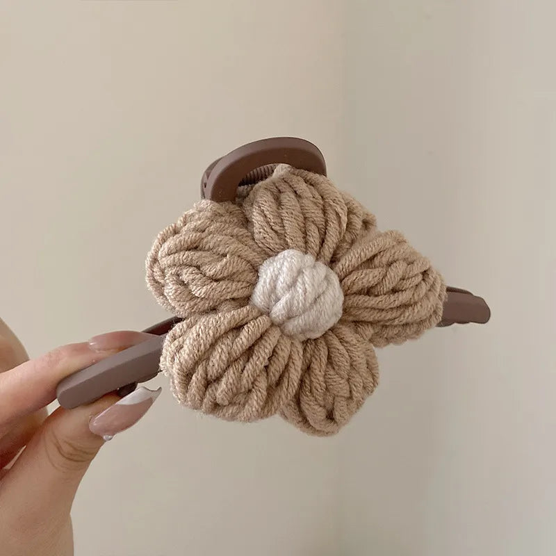 Beige knitted scrunchie on a wooden holder held by a hand against a plain background