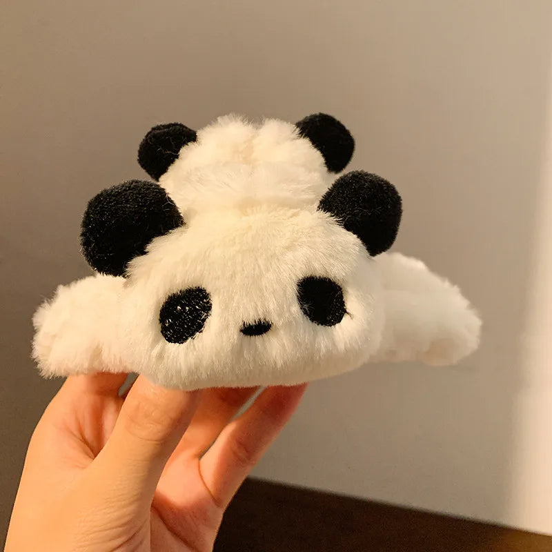 Plush panda-shaped hair scrunchies held by a hand against a neutral background