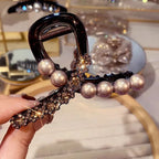 Hair clip with pearls and crystals held by a hand against a blurred background