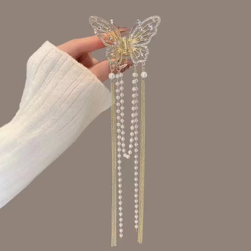 Butterfly hair clip with beaded tassels held by a hand against a neutral background