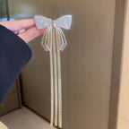 Decorative bow hair clip held by a hand against a neutral background