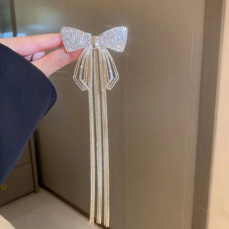 Decorative bow hair clip held by a hand against a neutral background