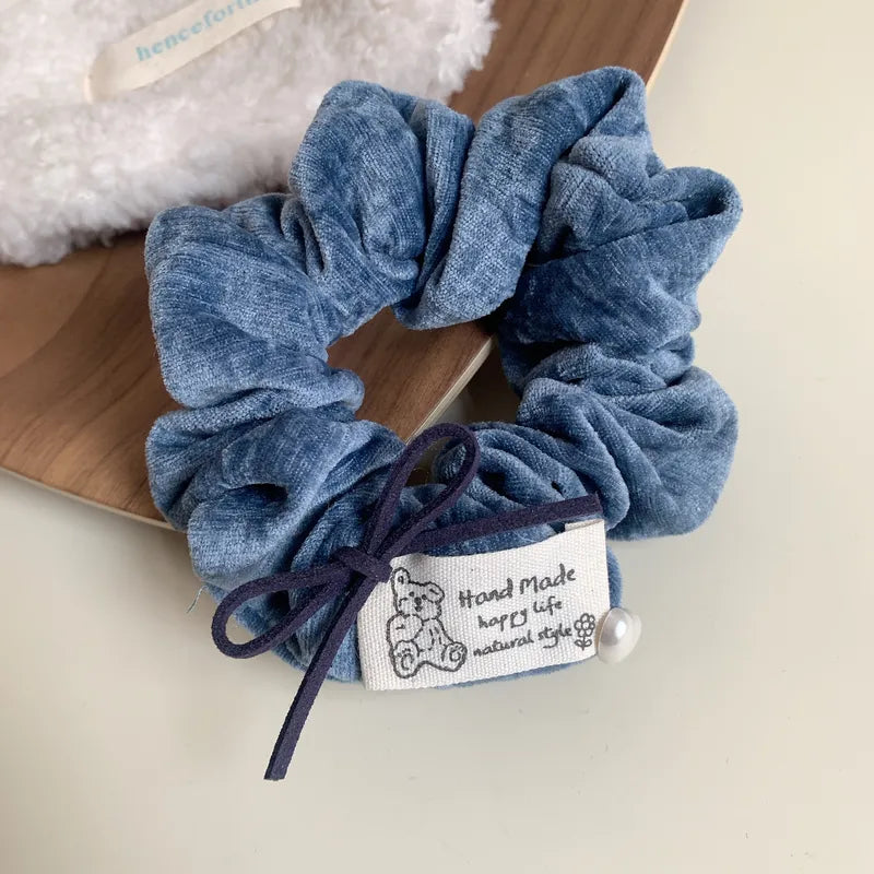 Blue scrunchie with a label on a wooden surface