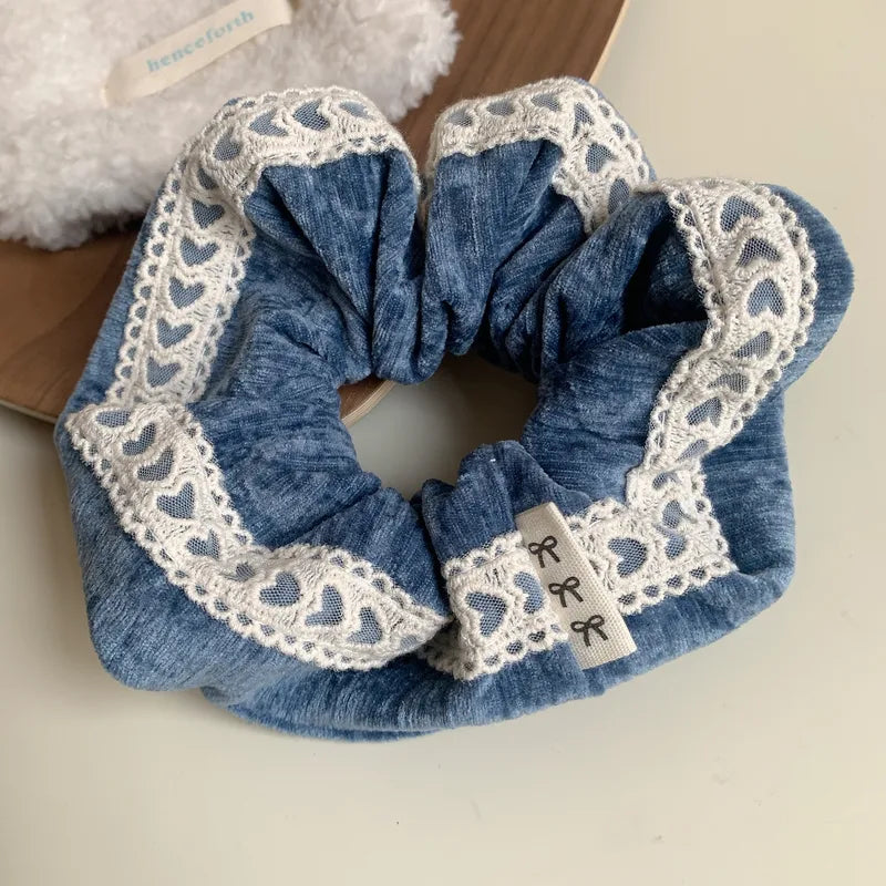Blue scrunchie with lace edge on a neutral background