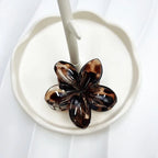 Brown flower-shaped clip on a white plate with a white background