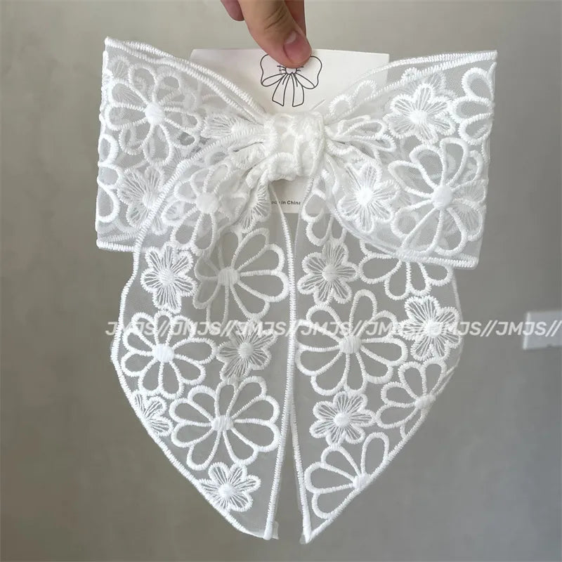 White lace bow held by a hand against a neutral background