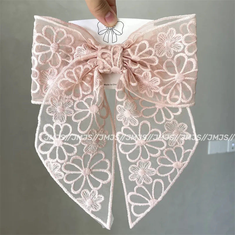 Lace bow with floral patterns held by a hand against a gray background