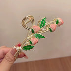 Decorative hair clip with strawberry design held by a hand against a neutral background