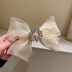 Decorative bow with a crystal center held by a hand against a neutral background