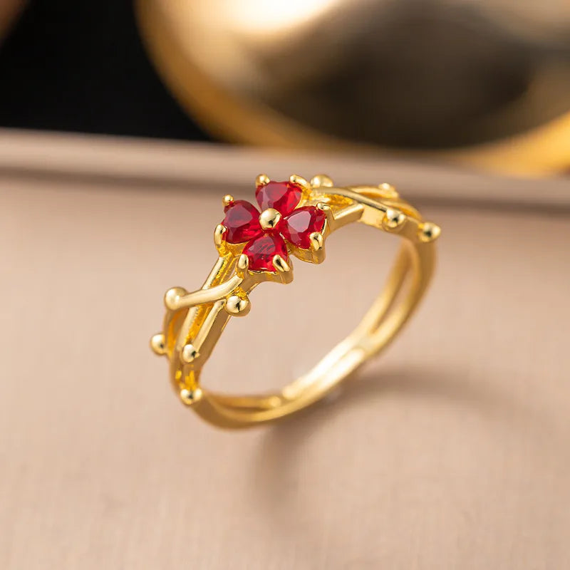Gold ring with red gemstones on a beige background