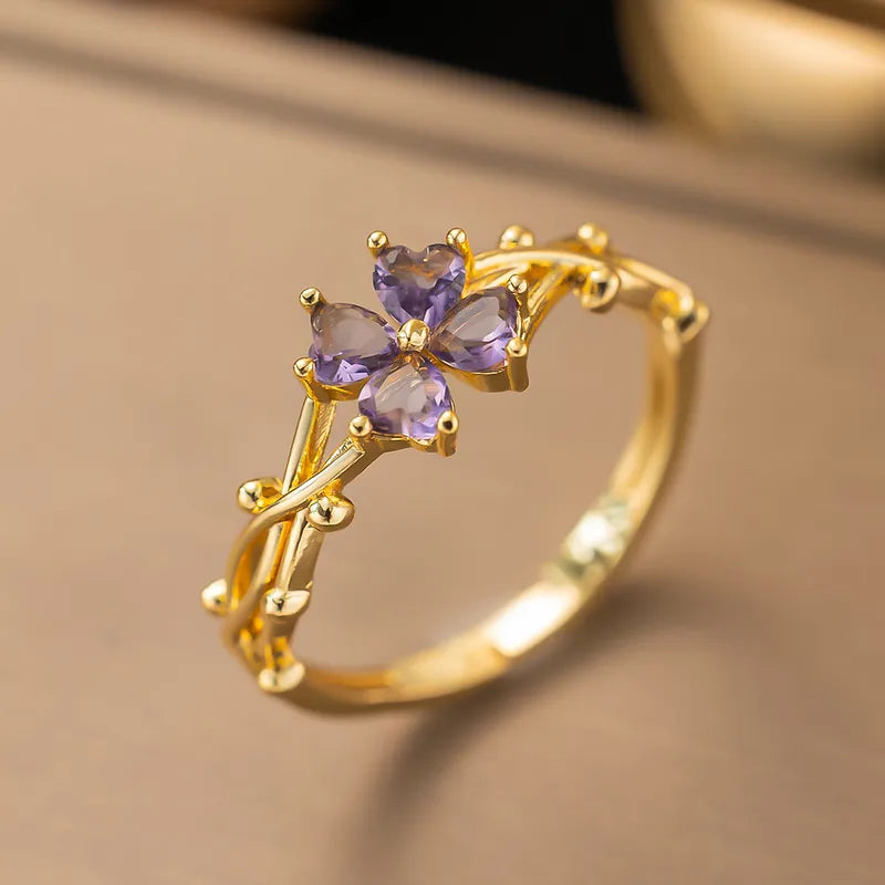 Gold ring with purple gemstones on a beige background