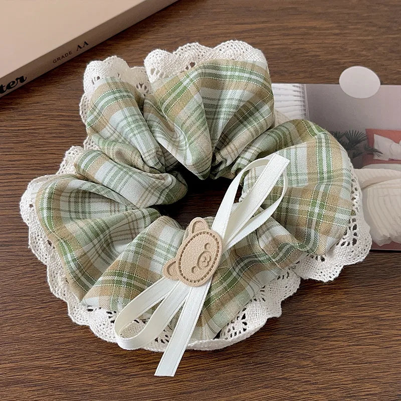Plaid scrunchie with lace edge and ribbon on a wooden surface