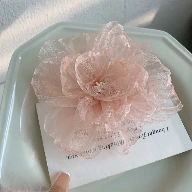 Pink floral hair clip on a textured surface