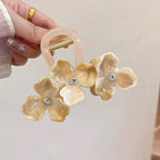 Floral hair clip with rhinestones held by a hand against a neutral background