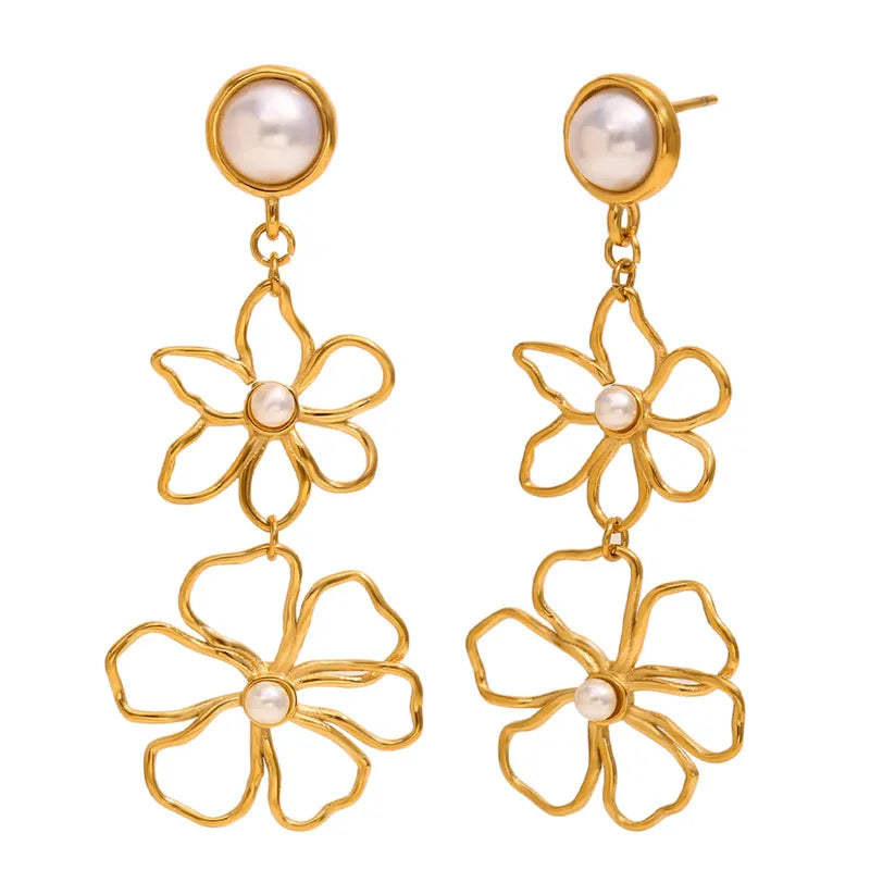Gold flower-shaped earrings with pearl centers on a white background