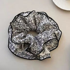 Black and white floral patterned scrunchie on a light surface