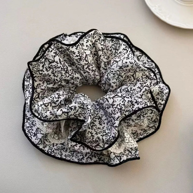 Black and white floral patterned scrunchie on a light surface