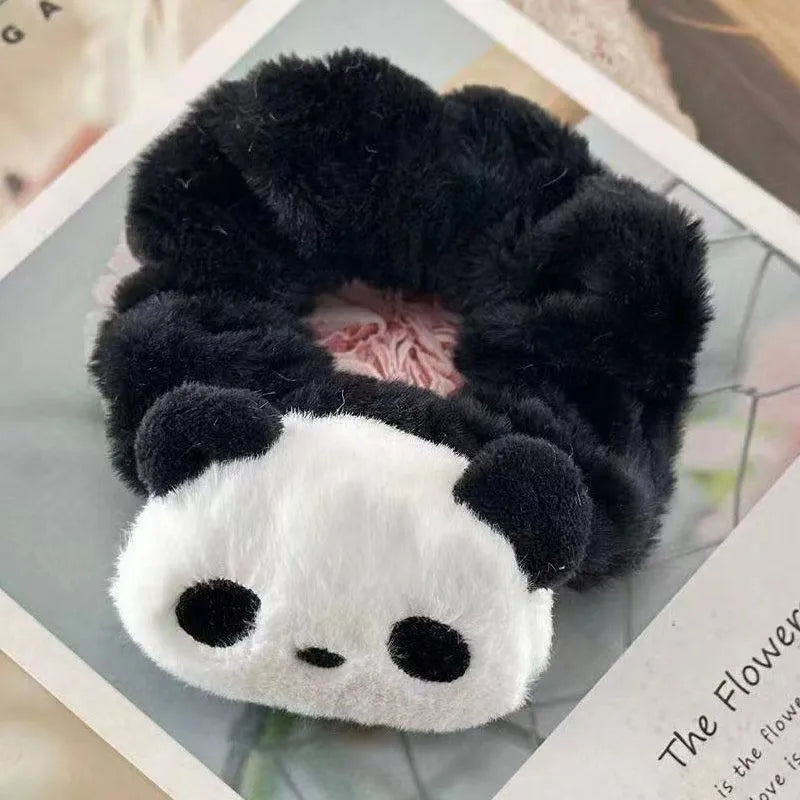 Plush panda-shaped hair scrunchie on a textured surface