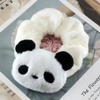 Plush panda-shaped hair scrunchie on a magazine background
