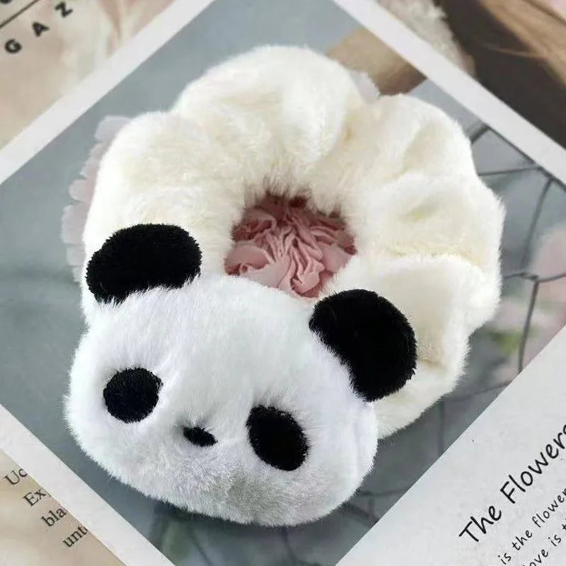 Plush panda-shaped hair scrunchie on a magazine background