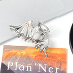 Silver dragon-shaped clip on a planner with mountain design