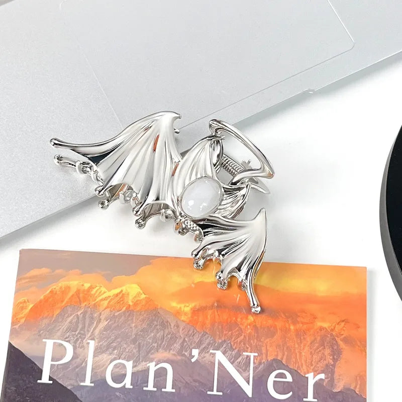 Silver dragon-shaped clip on a planner with mountain design