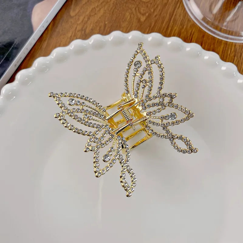 Gold butterfly-shaped hair clip with rhinestones on a white plate