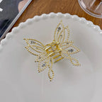 Gold butterfly hair clip on a white plate with a wooden surface in the background