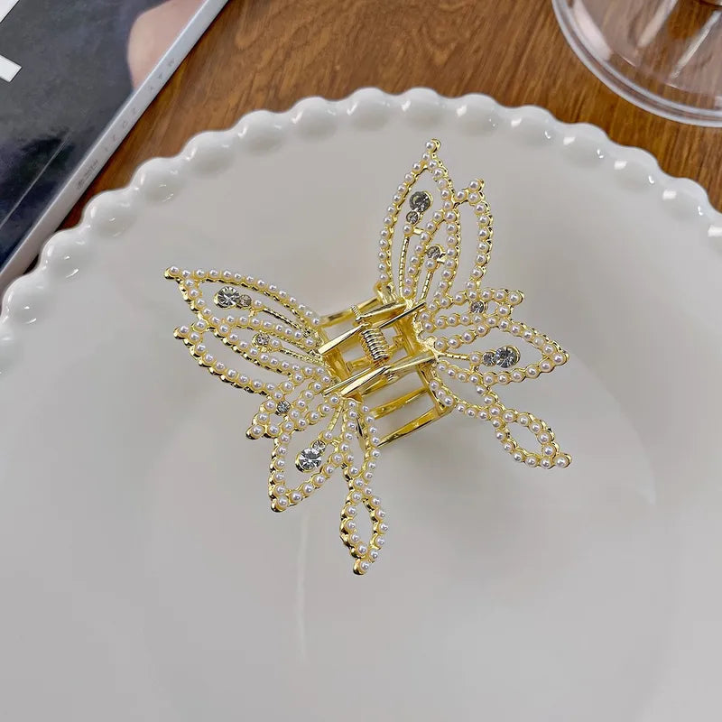Gold butterfly hair clip on a white plate with a wooden surface in the background