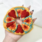 Colorful crochet heart-patterned item held by a hand with painted nails.
